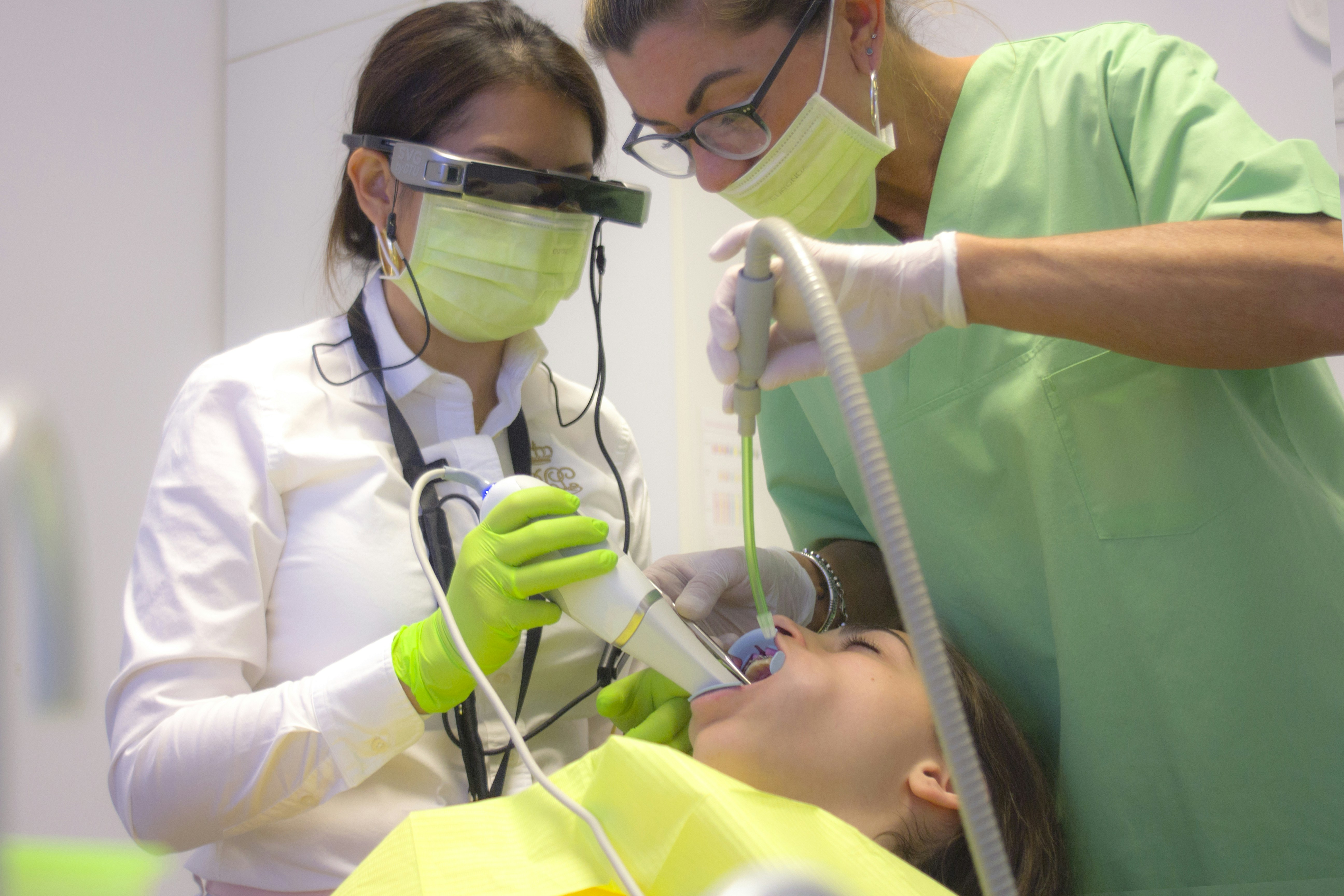 Young dental professional in clinical uniform smiling at camera in modern dental practice setting
