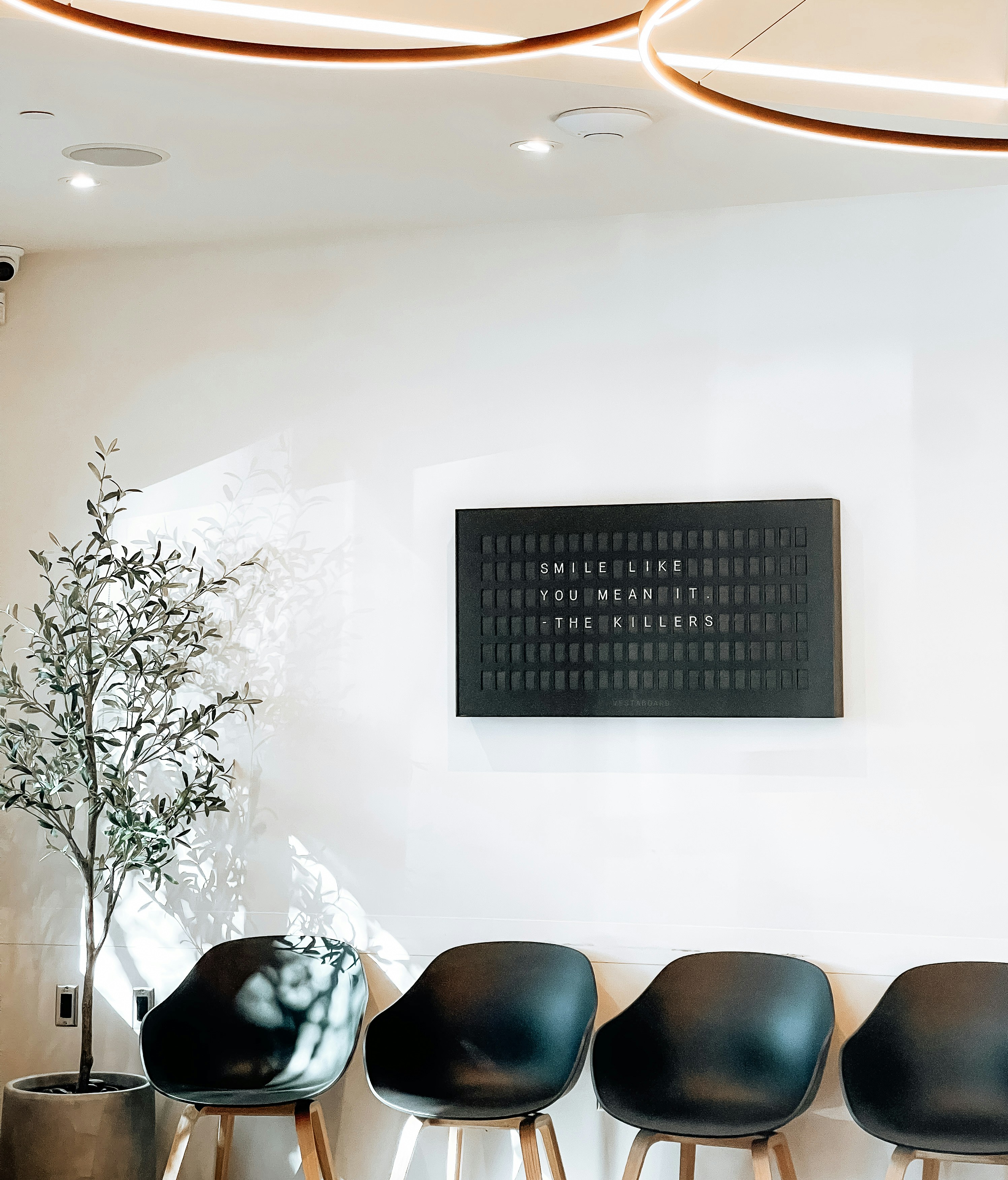 Dental clinic waiting room area with a white wall and black sign that reads Smile Like You Mean It like a quote